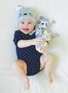 Picture of happy baby in crib with teddy.